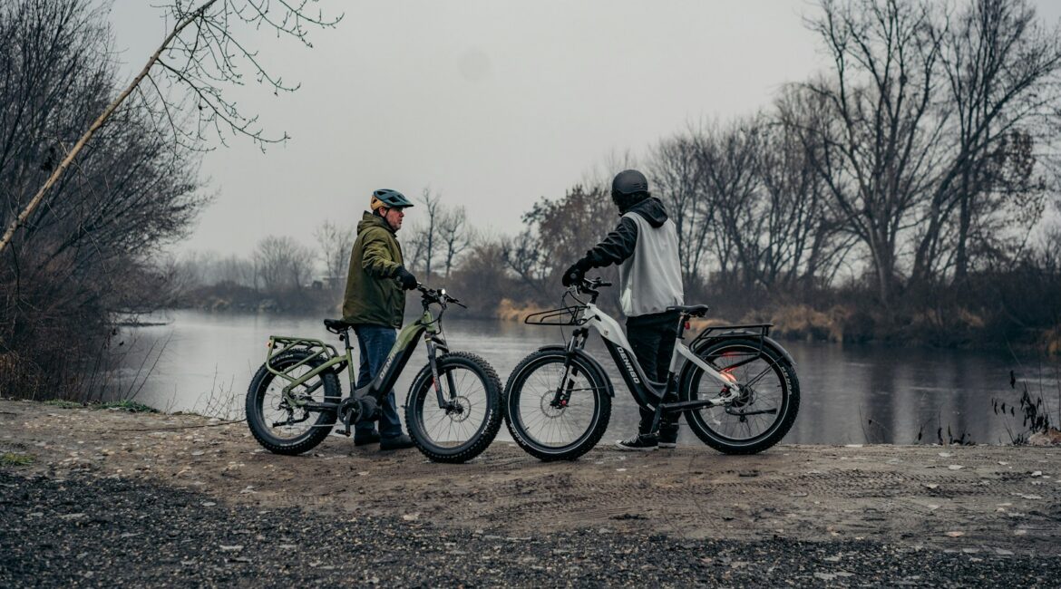 a couple of men standing next to bikes near a lake