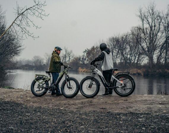 a couple of men standing next to bikes near a lake